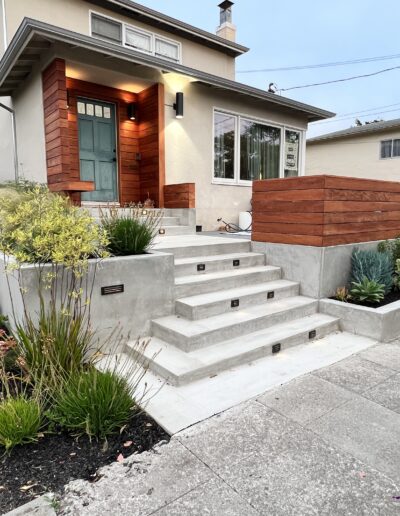 A house with concrete steps and plants in front of it.