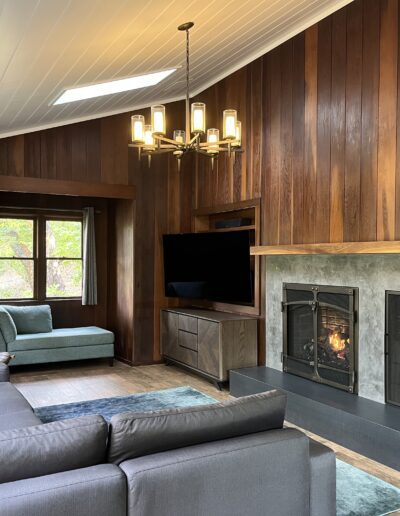 A living room with wood paneling and a fireplace.